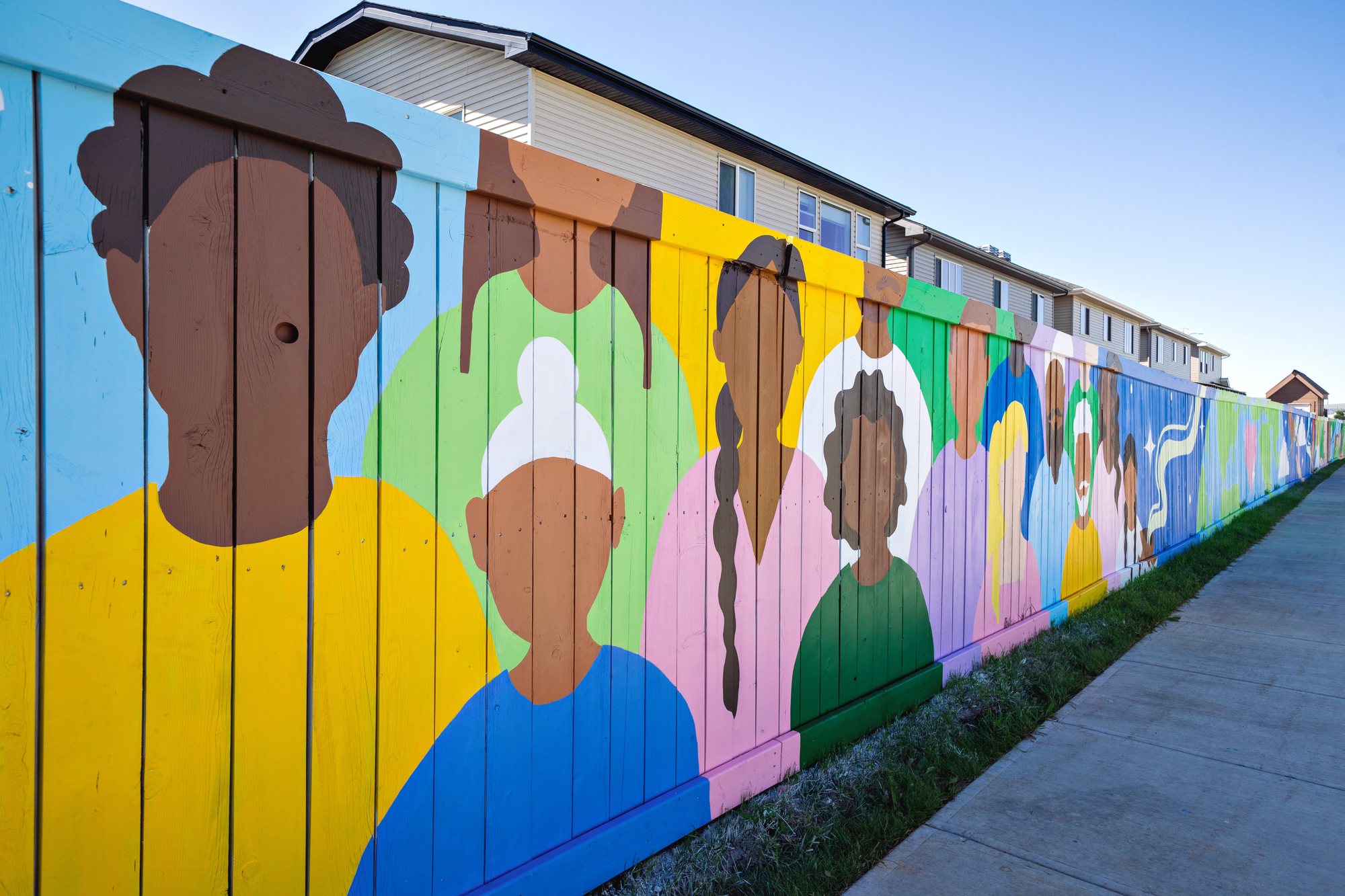 A row of painted community figures along the fence
